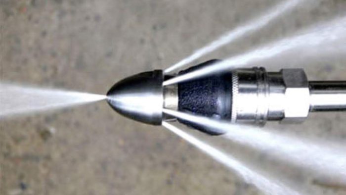 High pressure water spraying out of a water jetting nozzle.