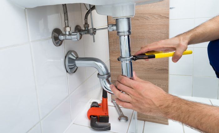 Plumber using a wrench on a bathroom pipe